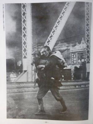 支那軍に町を焼かれ、逃げ遅れた老婆を避難地まで背負う日本軍兵士 『写真集支那事変』